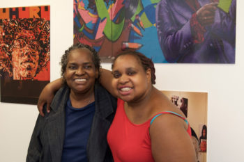 Two woman at an art exhibit with arms around each other