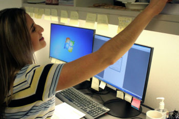 Women working at her desk with her computers and post it notes