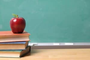 Apple on books in front of classroom chalkboard