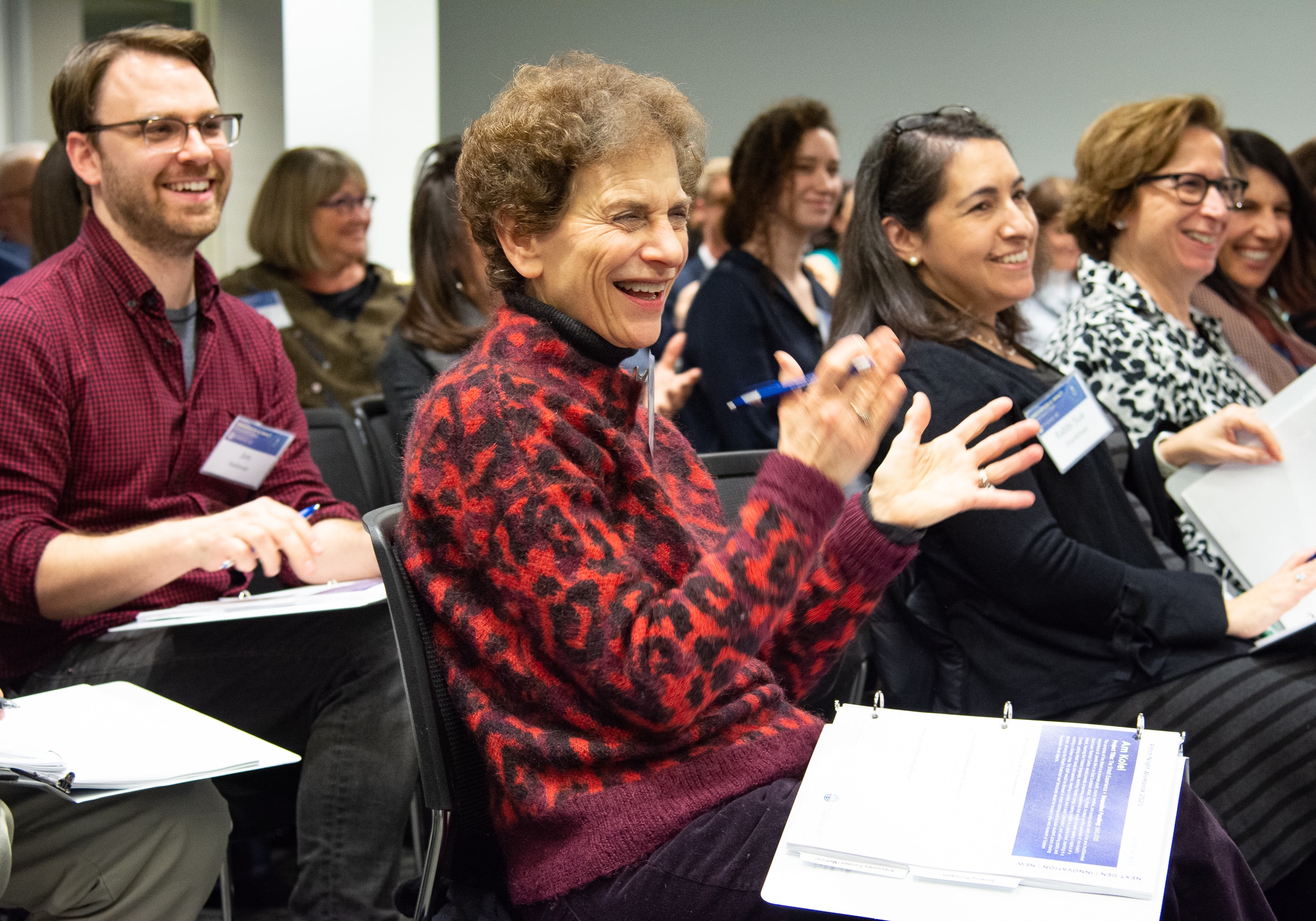 Leaders from across Greater Washington enjoy a presentation during Federation’s Pitch Night 2020. Woman smiling and clapping in foreground.