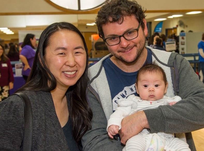 Multicultural parents holding baby at community event