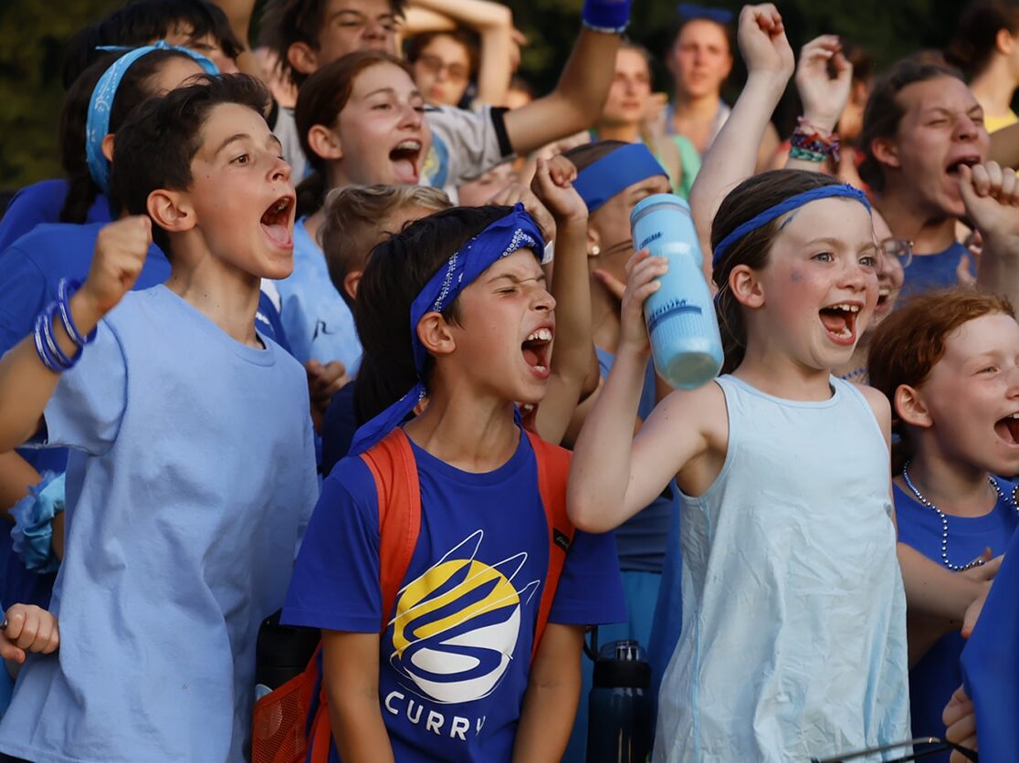 A group of children cheering at summer camp