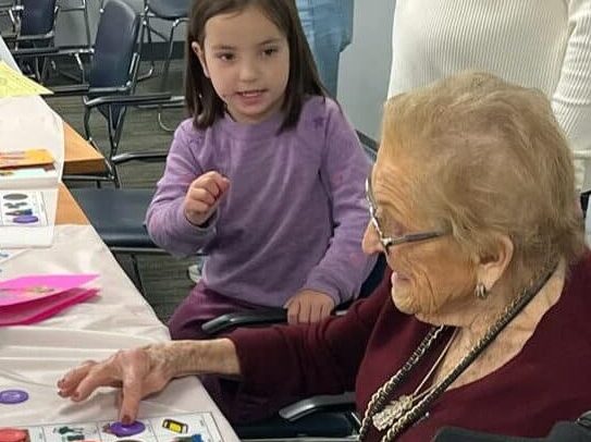A little girl and senior playing bingo together
