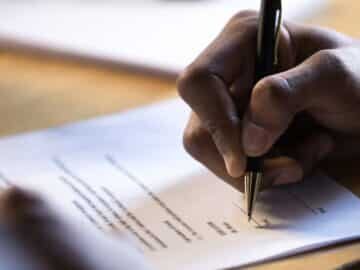 Closeup of a hand signing a grant