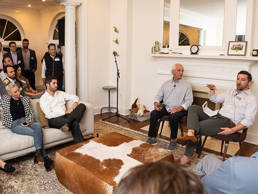 People speaking in a home, to a group, at the Cocktails and Conversation event.