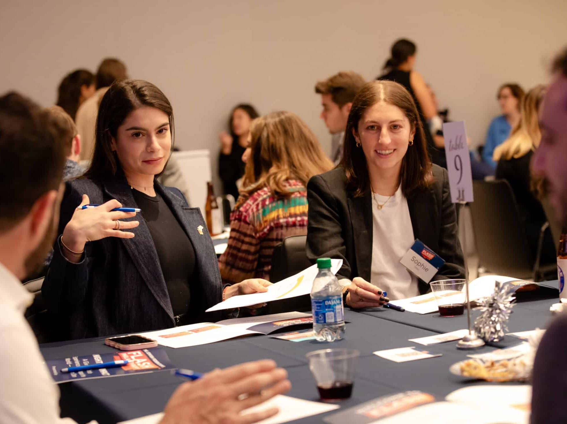 Group of people collaborating and speaking, sitting at a table.