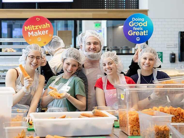 A group of people in hairnets holding signs in a kitchen