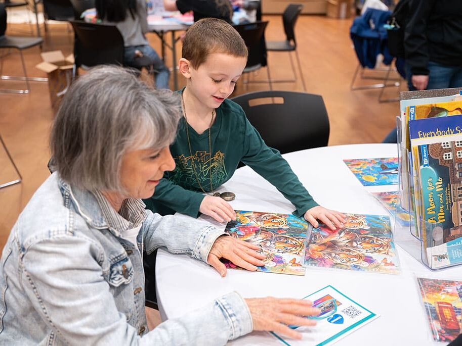 A boy and woman look at a book together