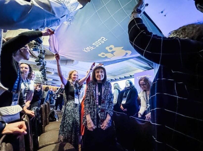 A group of women raising a flag over another woman