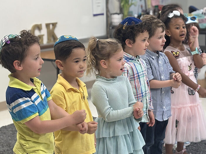 Preschool age children stand in a line singing a song.