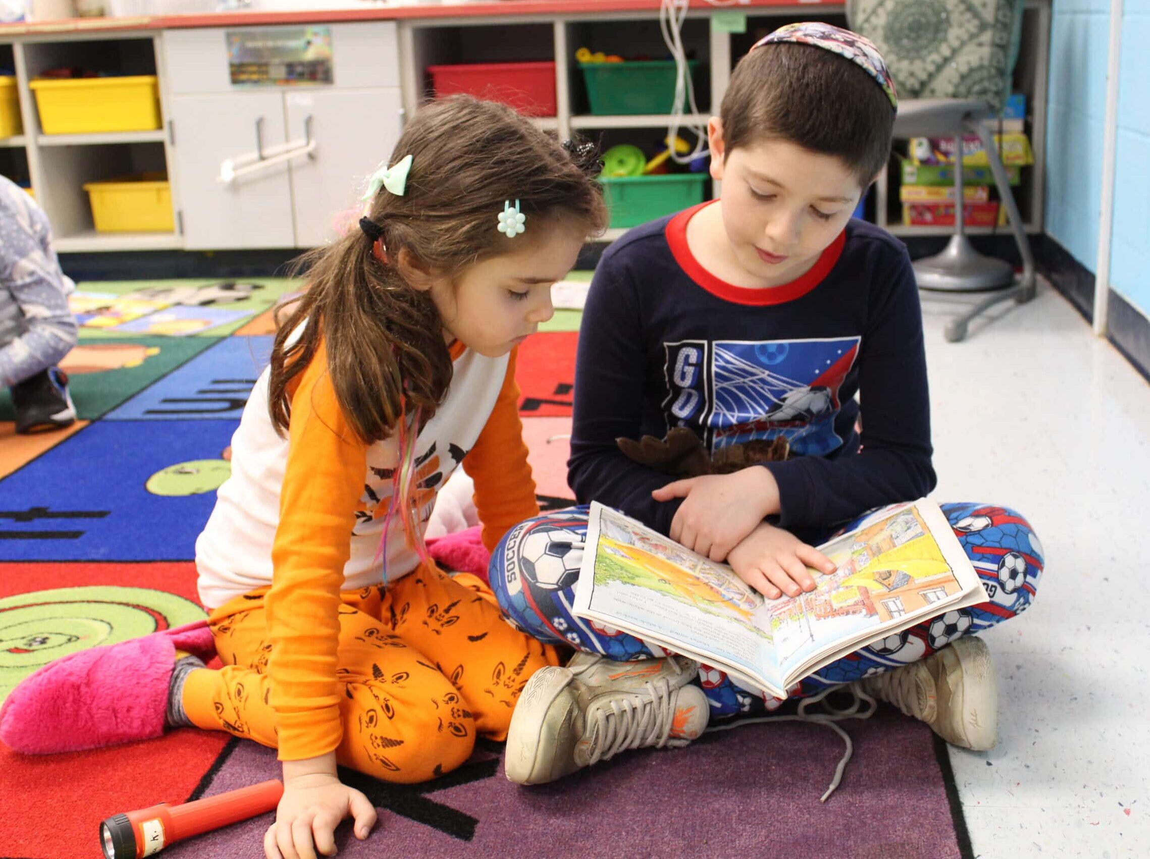Two children sitting on the floor reading a book