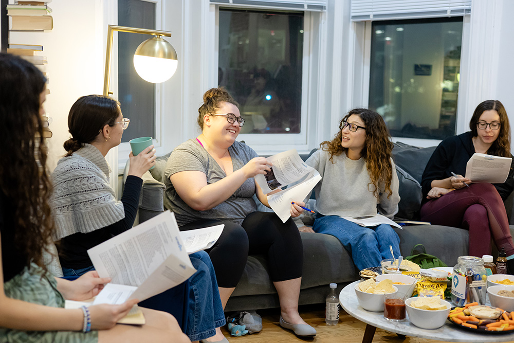 Group of young adults sitting in room together, having a discussion.