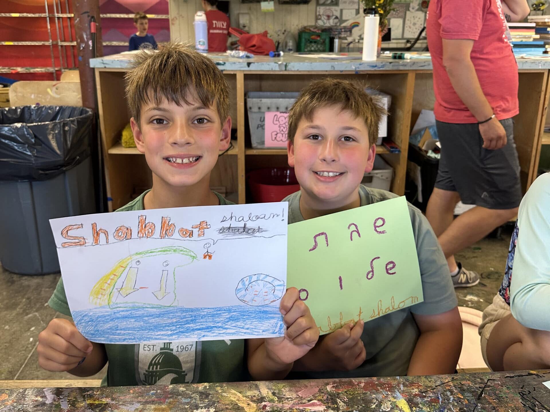 Two boys holding up their drawings