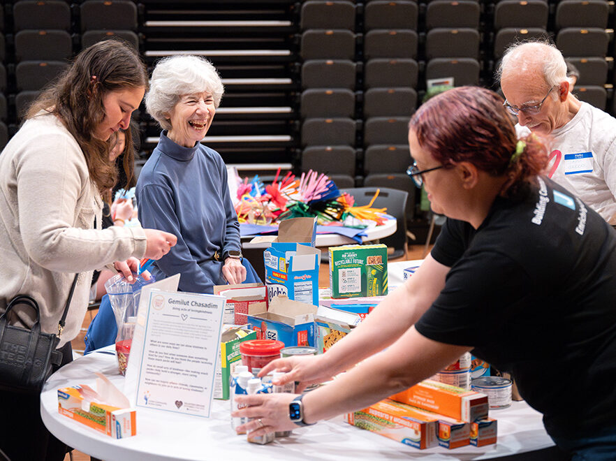 Group of people working together around a table, doing a craft, at a Good Deeds Week event at the Pozez JCC.