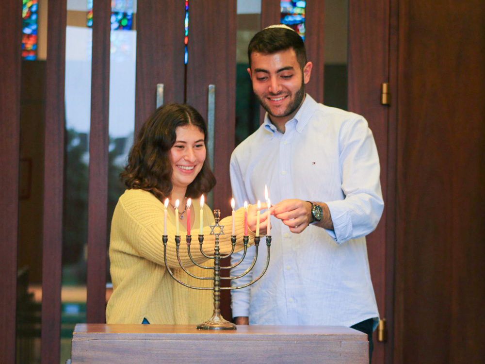 Two American University students lighting the Hanukkah menorah