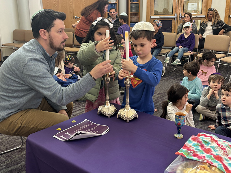 Father lights shabbat candles with children