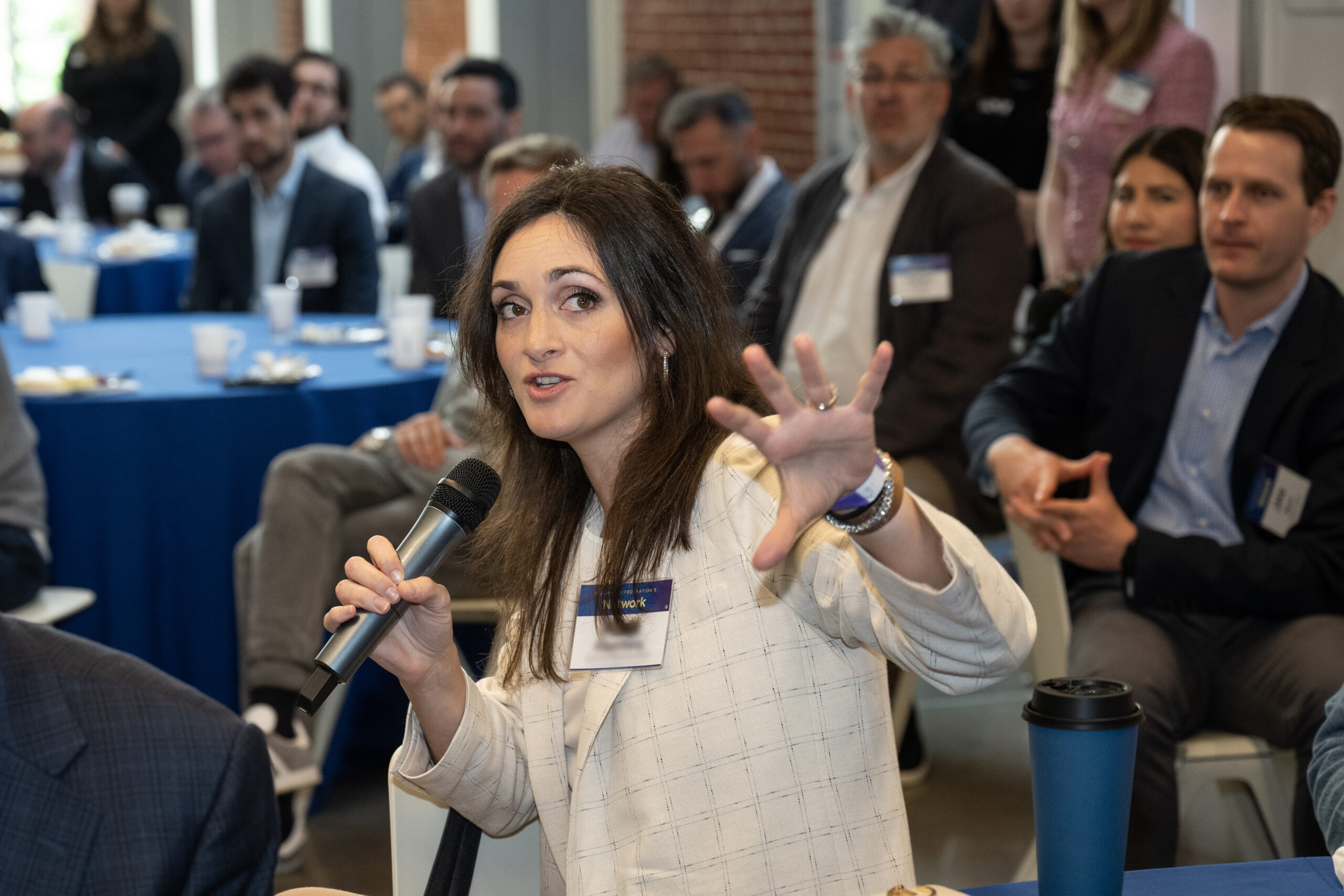 A woman speaking with a microphone at The Network's Real Estate Division Breakfast at the Capital Jewish Museum