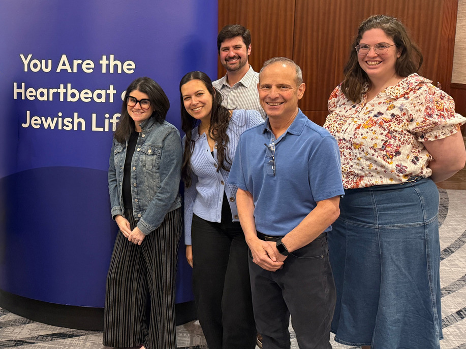 Federation team at FedPro in front of blue sign that reads You are the heart of Jewish life.